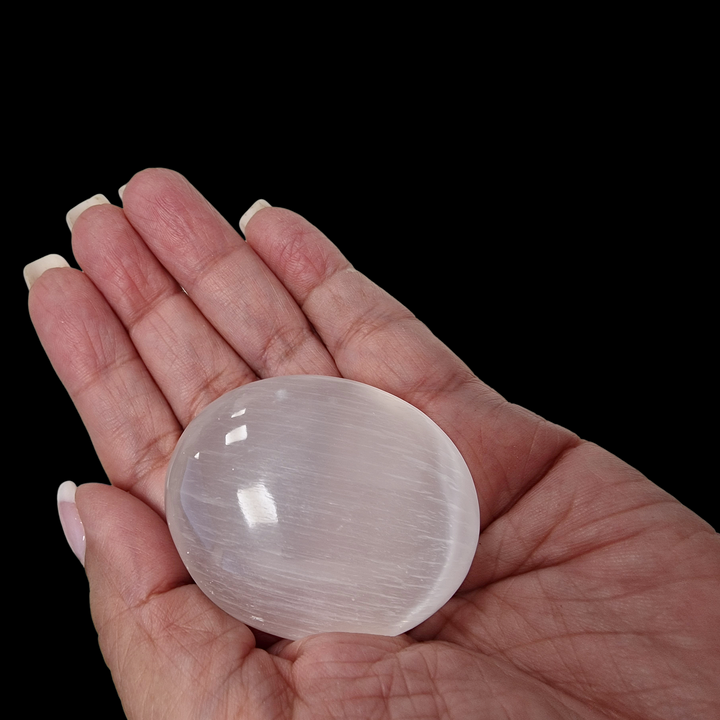 Selenite Palm Stone 50 mm shown on hand for scale.