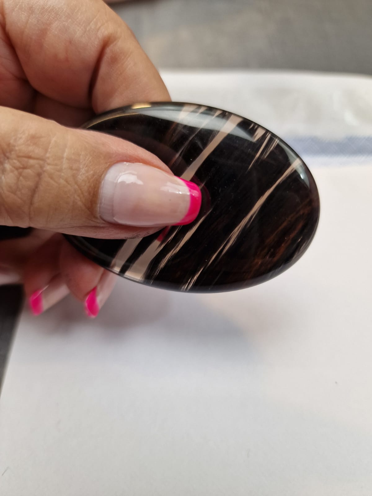 Midnight Lace Obsidian Thumb Stone by GeoFossils – smooth, dark oval stone with delicate lace-like patterns, perfect for grounding, protection, and connecting with the Root Chakra, associated with the Earth element.