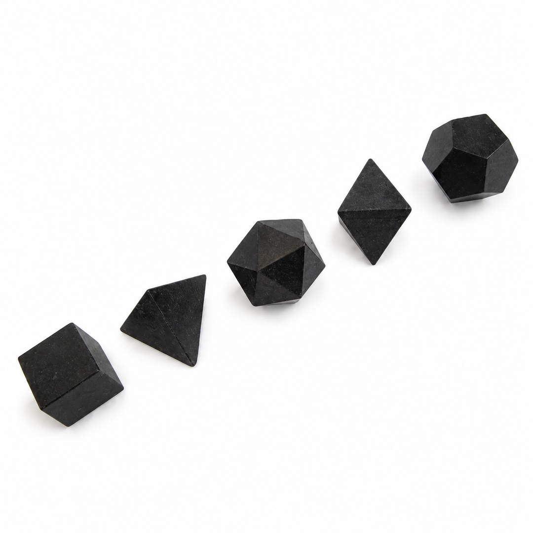 GeoFossils five-piece Black Tourmaline Platonic set with carved cube, tetrahedron, icosahedron, octahedron and dodecahedron on a white background.