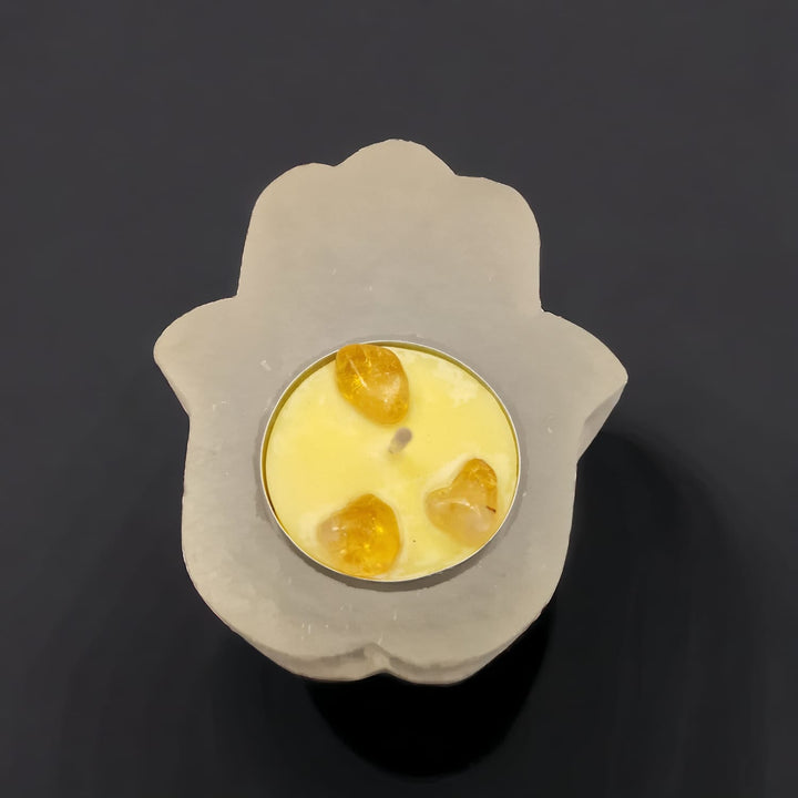 Selenite Hamsa Hand Tealight Holder with protective carved design, ideal for spiritual spaces and crystal cleansing displayed with a crystals candle in yellow with 3 Citrine Crystals