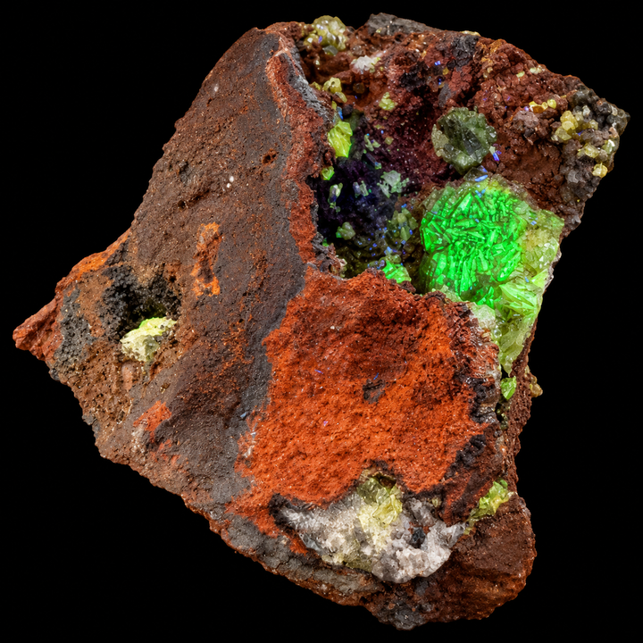 GeoFossils Adamite specimen 191 under Mid Wave UV, displaying green fluorescence across the visible crystal clusters and cavity.