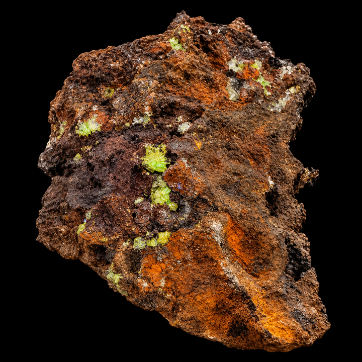 GeoFossils Adamite specimen 195 under Mid Wave UV, displaying small areas of green fluorescence among crystals across the rough matrix.