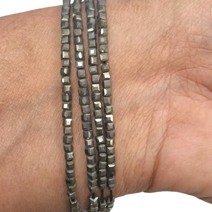 Pyrite 4mm cube beads held in a hand for scale