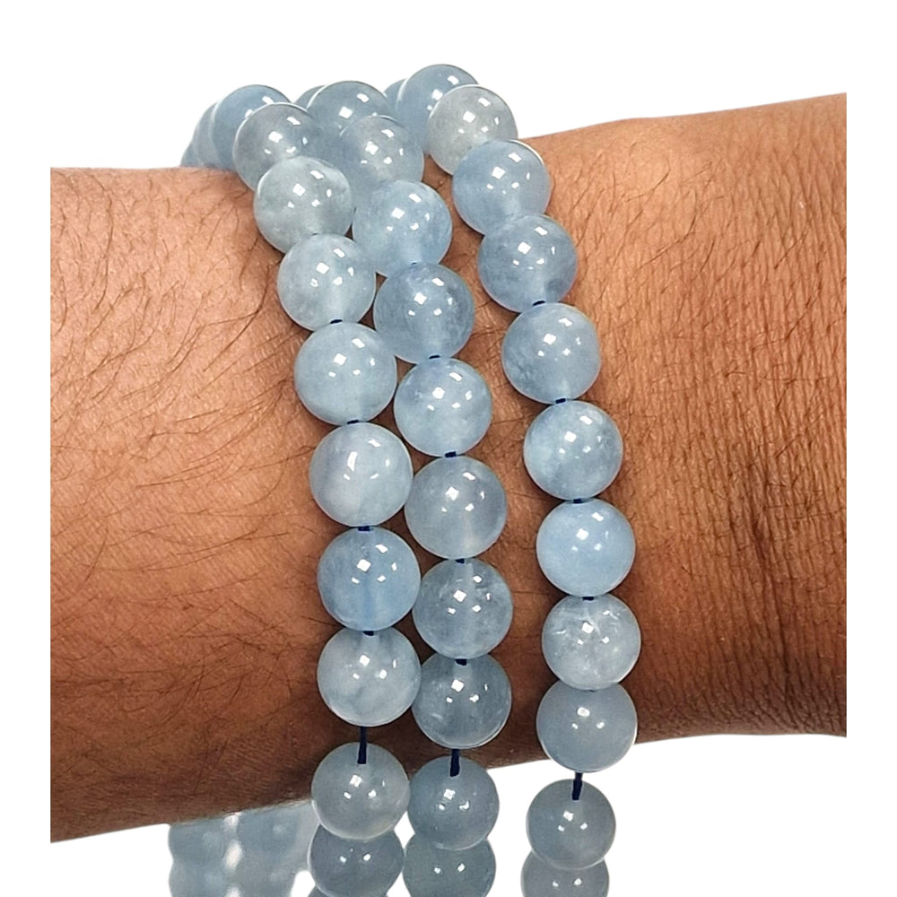 Kunzite round beads held in a hand for scale