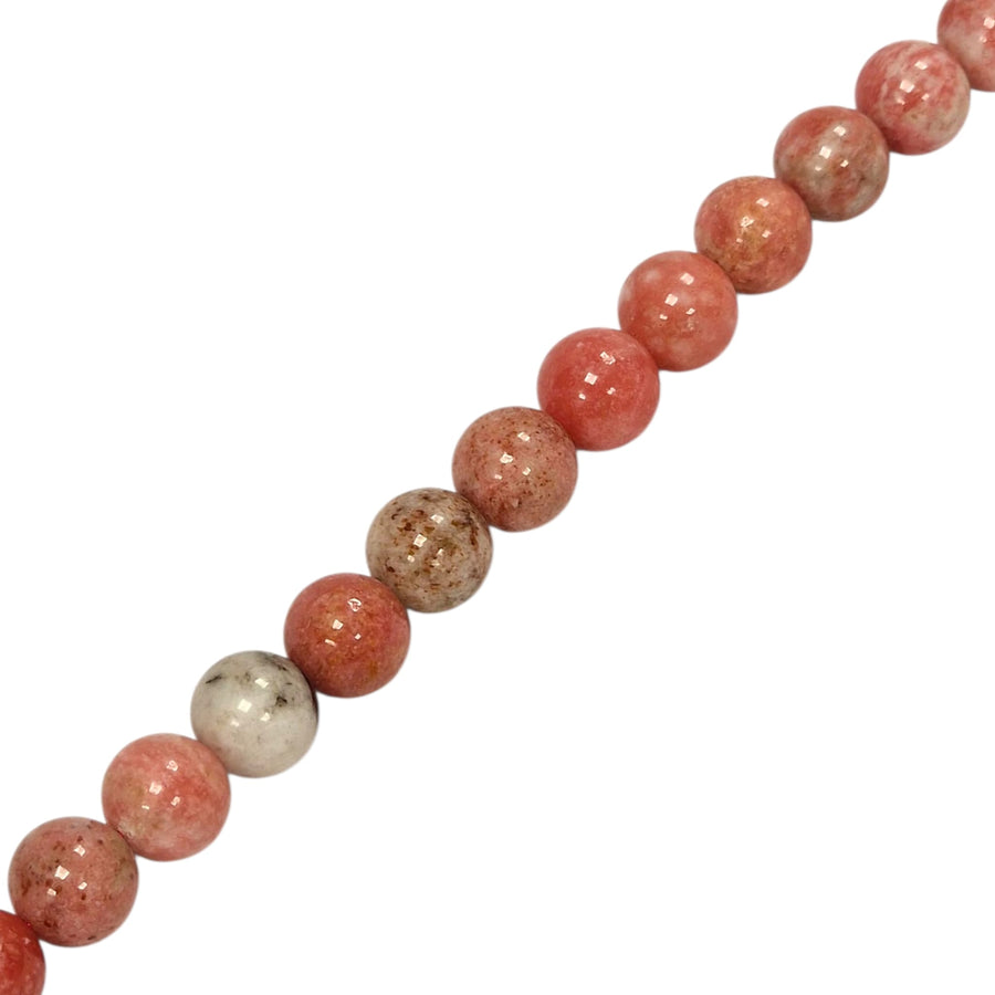 Pink Thulite round beads on a white background