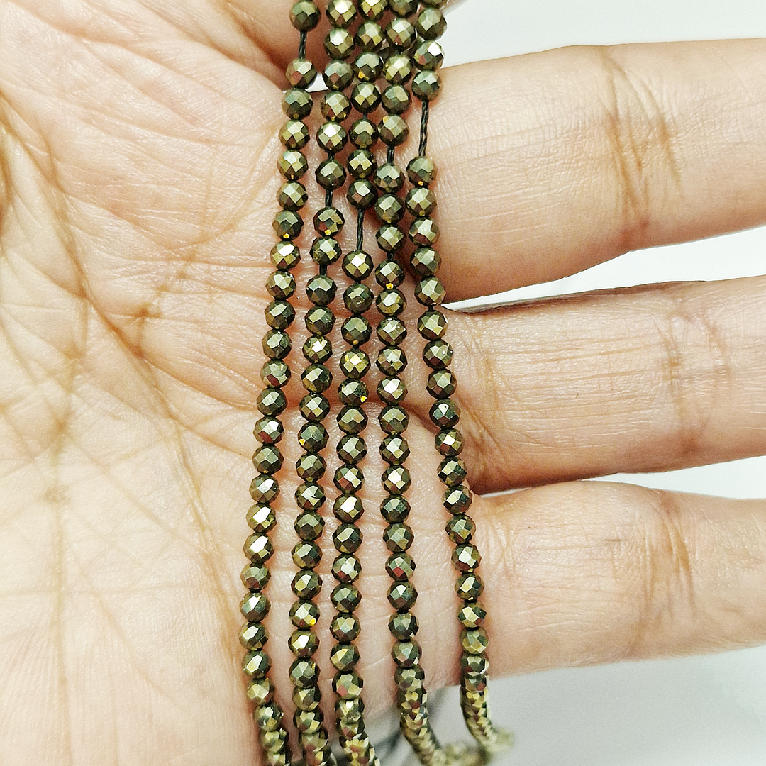 Pyrite 4mm Faceted Beads held in hand for scale
