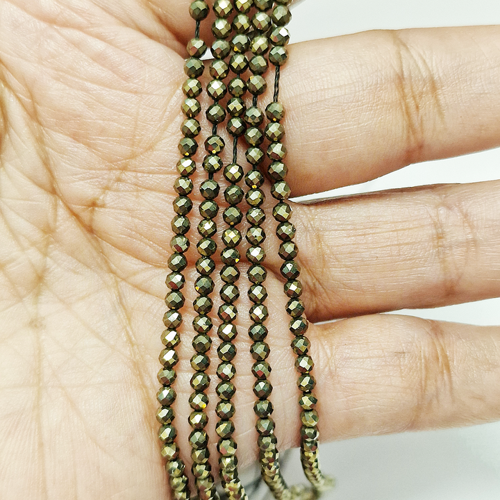 Pyrite 4mm Faceted Beads held in hand for scale