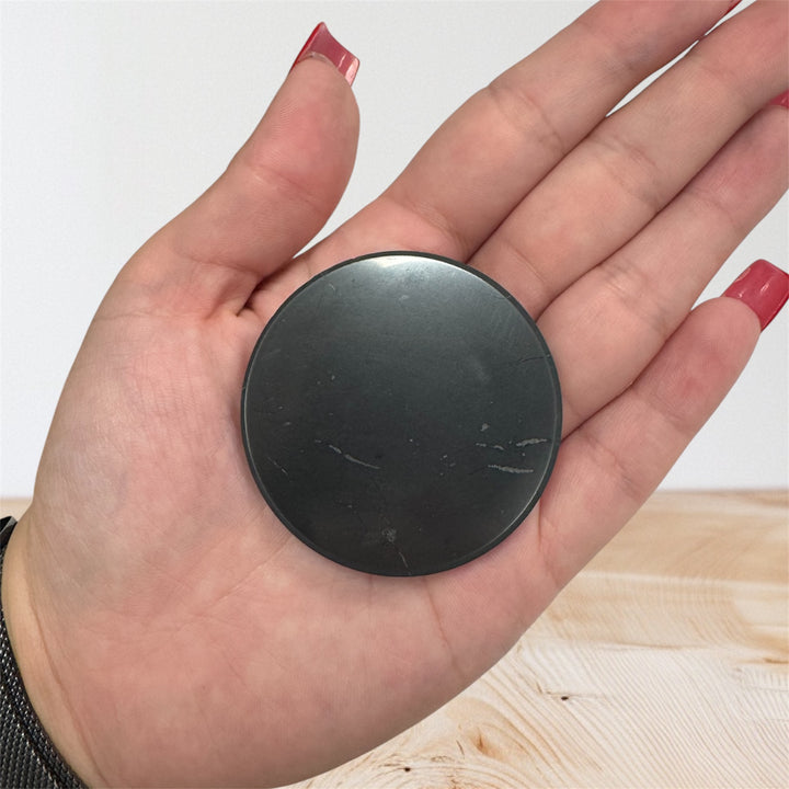 Close-up of a polished round shungite healing stone used for energy balance, grounding, and EMF protection.