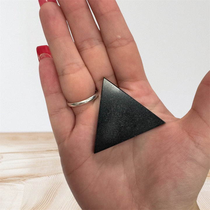 Close-up of a flat triangular shungite crystal, a natural healing stone for spiritual cleansing and energy protection.