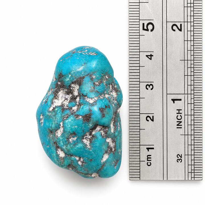 GeoFossils Kingman Mine Turquoise drilled tumblestone photographed beside a centimetre ruler, showing its approximate 3.5 cm height and natural shape.