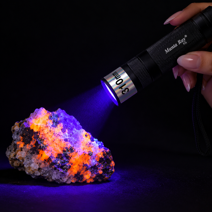 GeoFossils 310nm Manta Ray UV torch illuminating a fluorescent mineral specimen in darkness