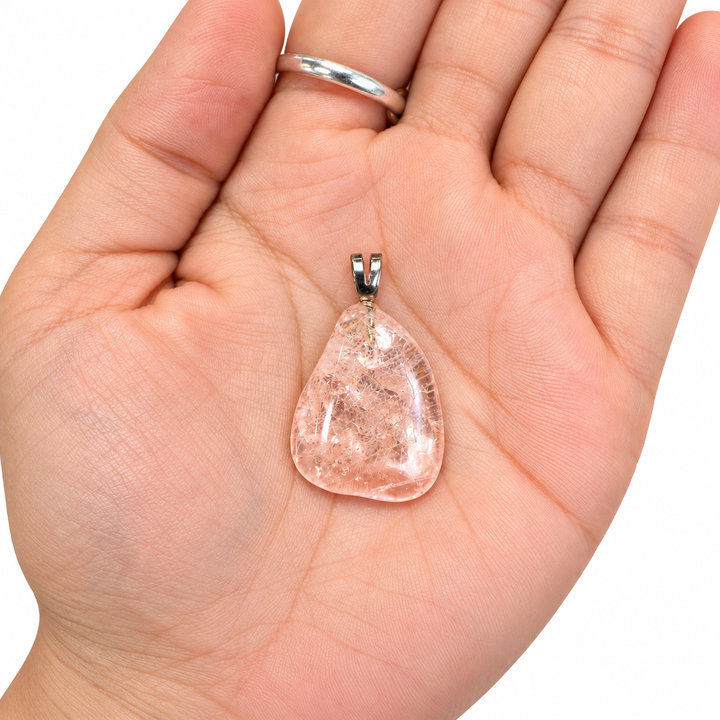 GeoFossils Morganite Tumblestone Pendant resting in the palm of a hand, showing the natural size of the polished pink gemstone and its sterling silver bail.