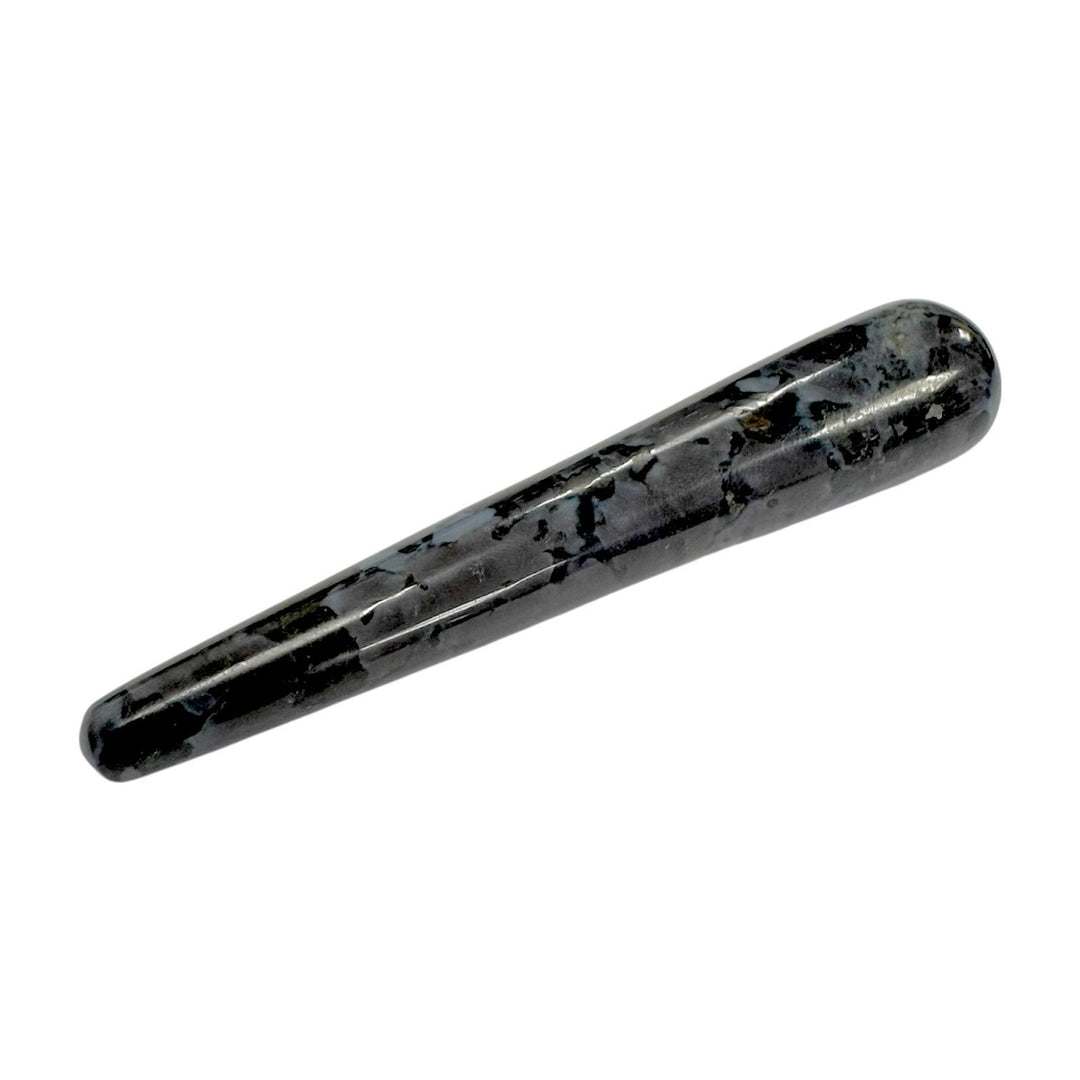 Polished Mystic Merlinite (Indigo Gabbro) crystal massage wand with a swirling mix of black, grey, and indigo tones, smooth and cylindrical with rounded ends, used for intuitive development, shadow work, and spiritual massage therapy
