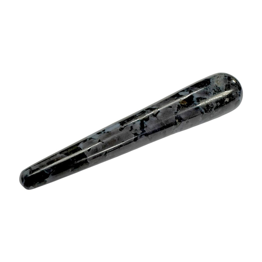 Polished Mystic Merlinite (Indigo Gabbro) crystal massage wand with a swirling mix of black, grey, and indigo tones, smooth and cylindrical with rounded ends, used for intuitive development, shadow work, and spiritual massage therapy
