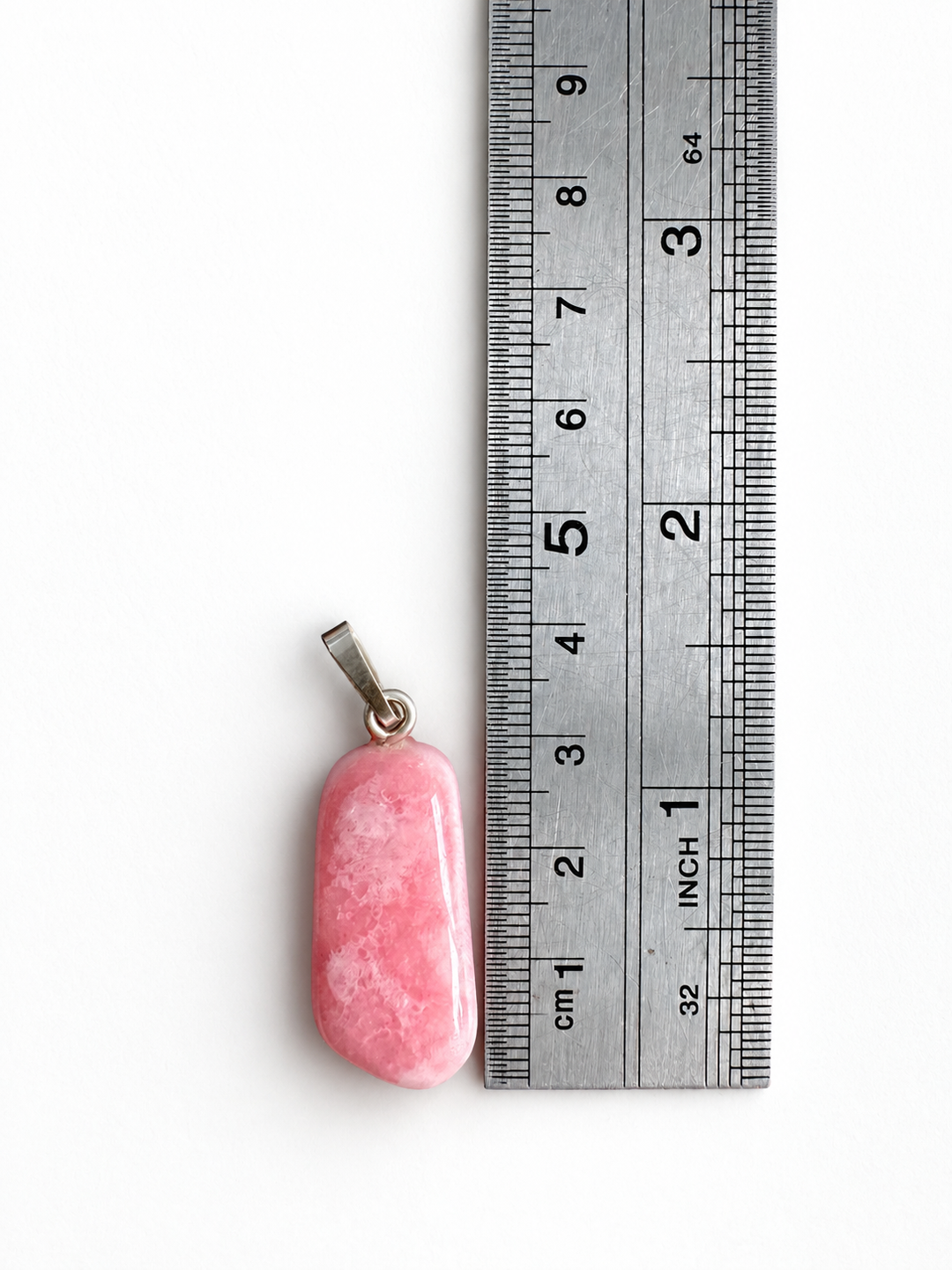 GeoFossils natural Rhodochrosite pendant positioned beside a centimetre ruler, measuring approximately 3.5 cm overall including its 925 sterling silver bail.