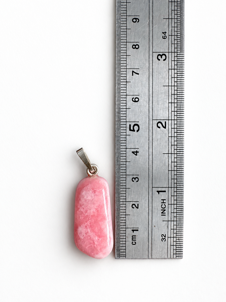 GeoFossils natural Rhodochrosite pendant positioned beside a centimetre ruler, measuring approximately 3.5 cm overall including its 925 sterling silver bail.