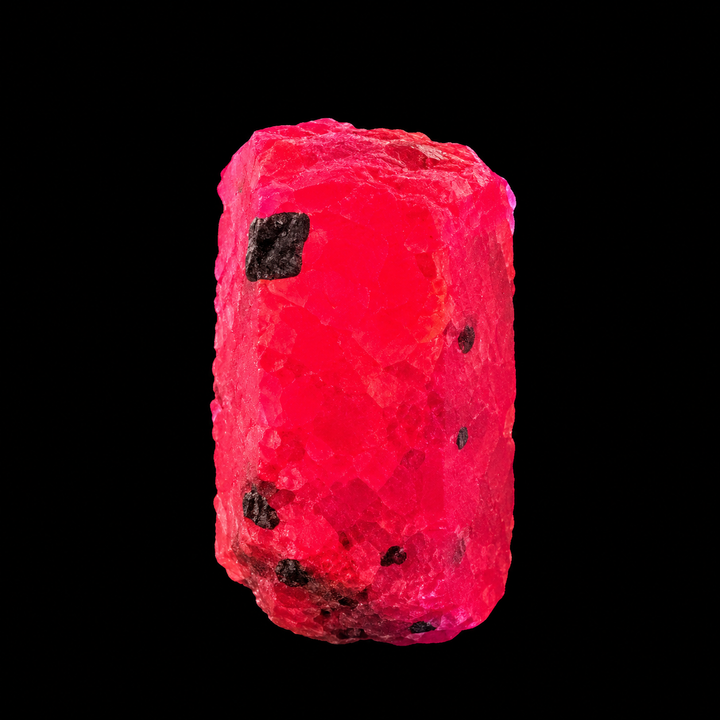 GeoFossils Ruby mineral specimen 214 showing natural pink and reddish tones with a rough crystal surface on a white background.