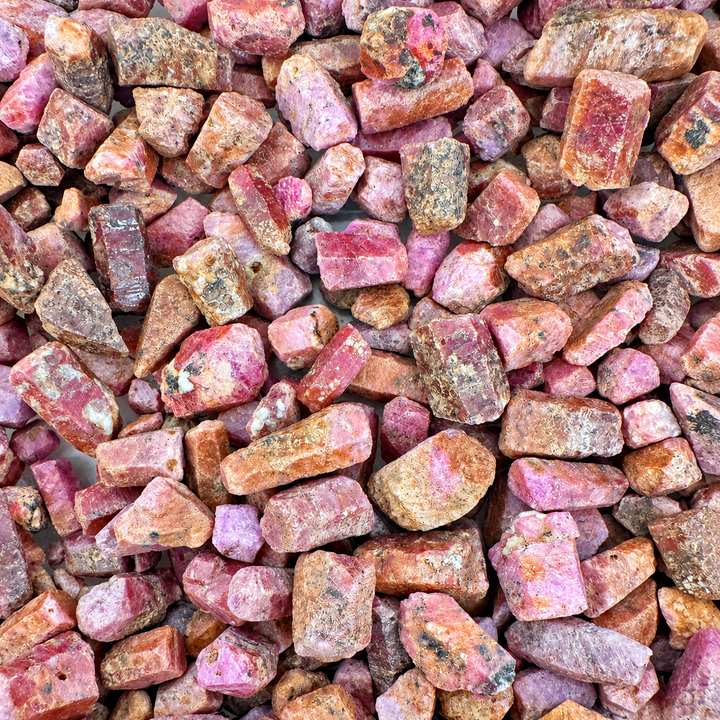 GeoFossils selection of rough Ruby mineral specimens displaying natural pink, purple and reddish-brown tones with varied crystal shapes and surface textures.