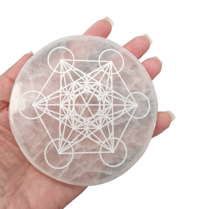 Selenite Charging Disc 10 cm engraved with Metatron’s Cube shown on hand for scale.