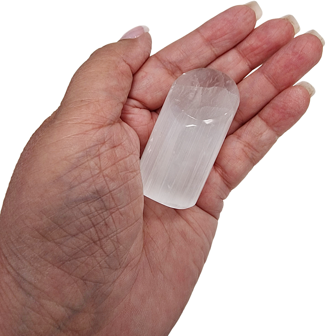 Hand holding a clear crystal against a white background