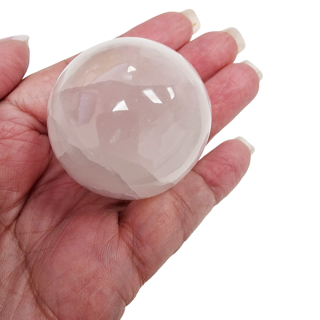 Selenite Sphere 40mm shown on hand for scale on white background