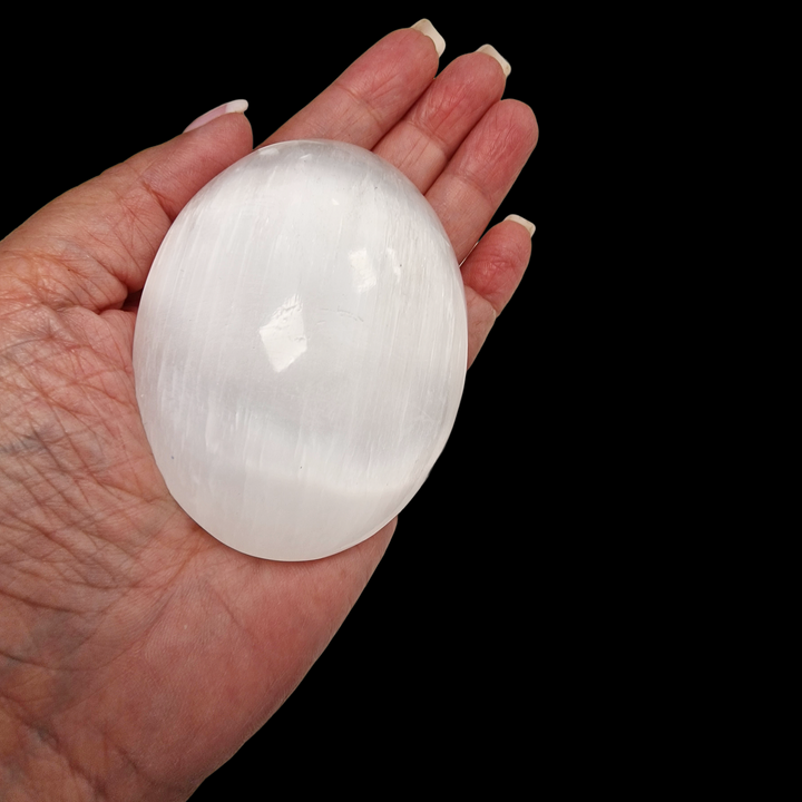 Selenite Palm Stone 90 mm shown on hand for scale.