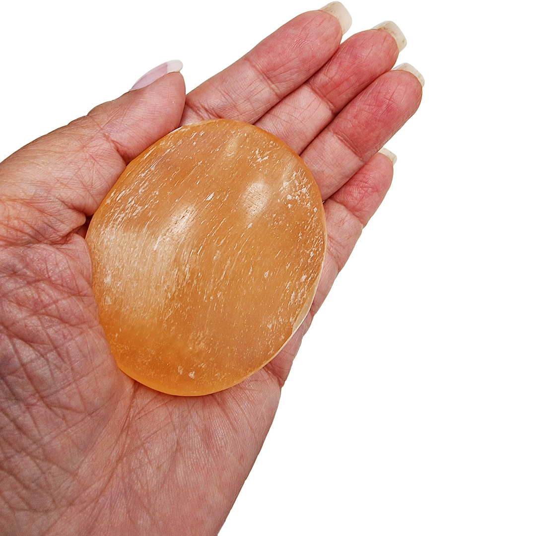 Peach Selenite Palm Stone 70 mm shown on hand for scale.