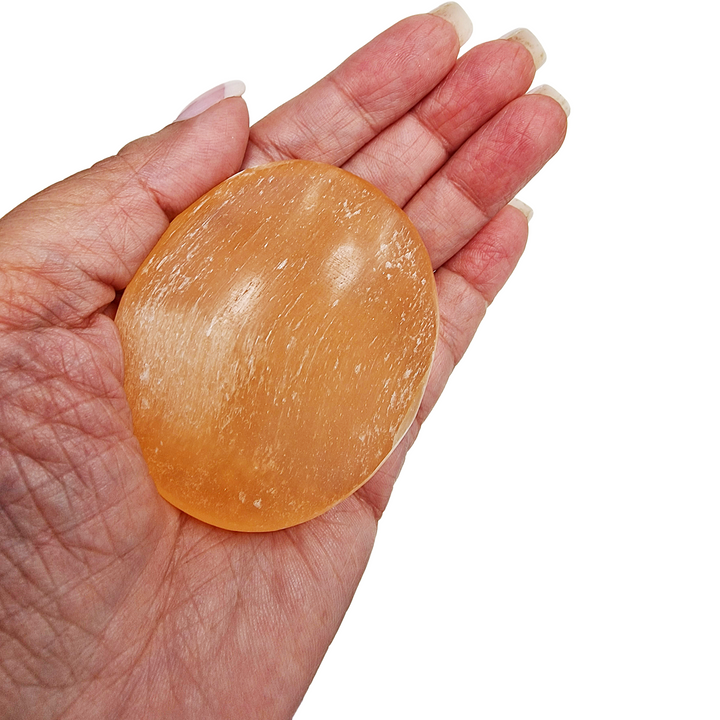 Peach Selenite Palm Stone 70 mm shown on hand for scale.