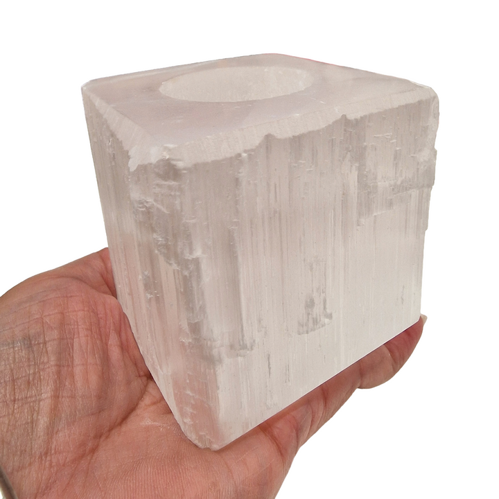 Selenite Square Tea Light Holder with polished top and base, raw sides, shown in hand for scale.