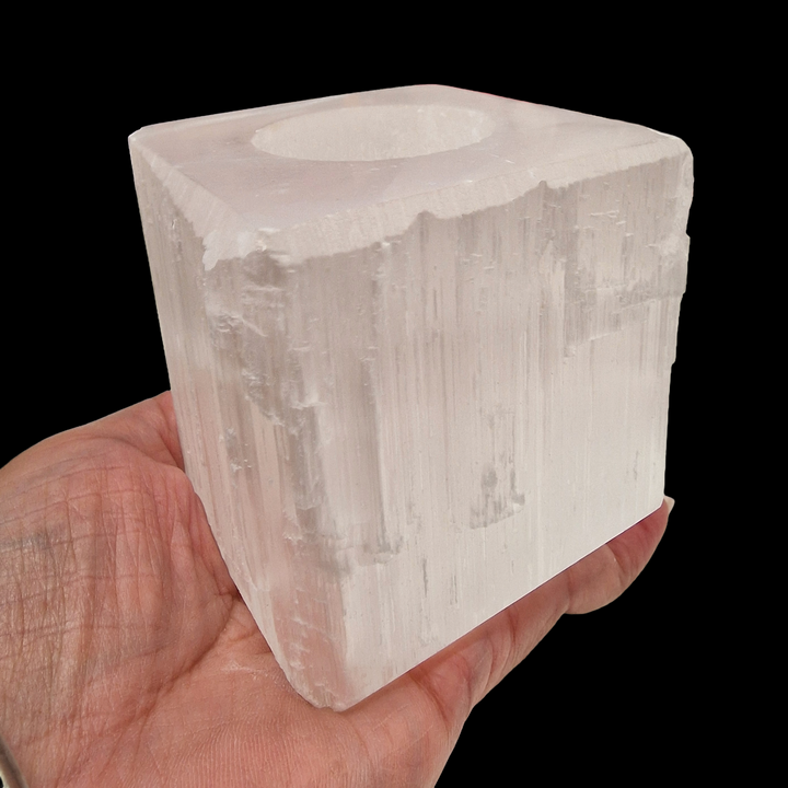 Selenite Square Tea Light Holder with polished top and base, raw sides, shown in hand for scale. Black Background