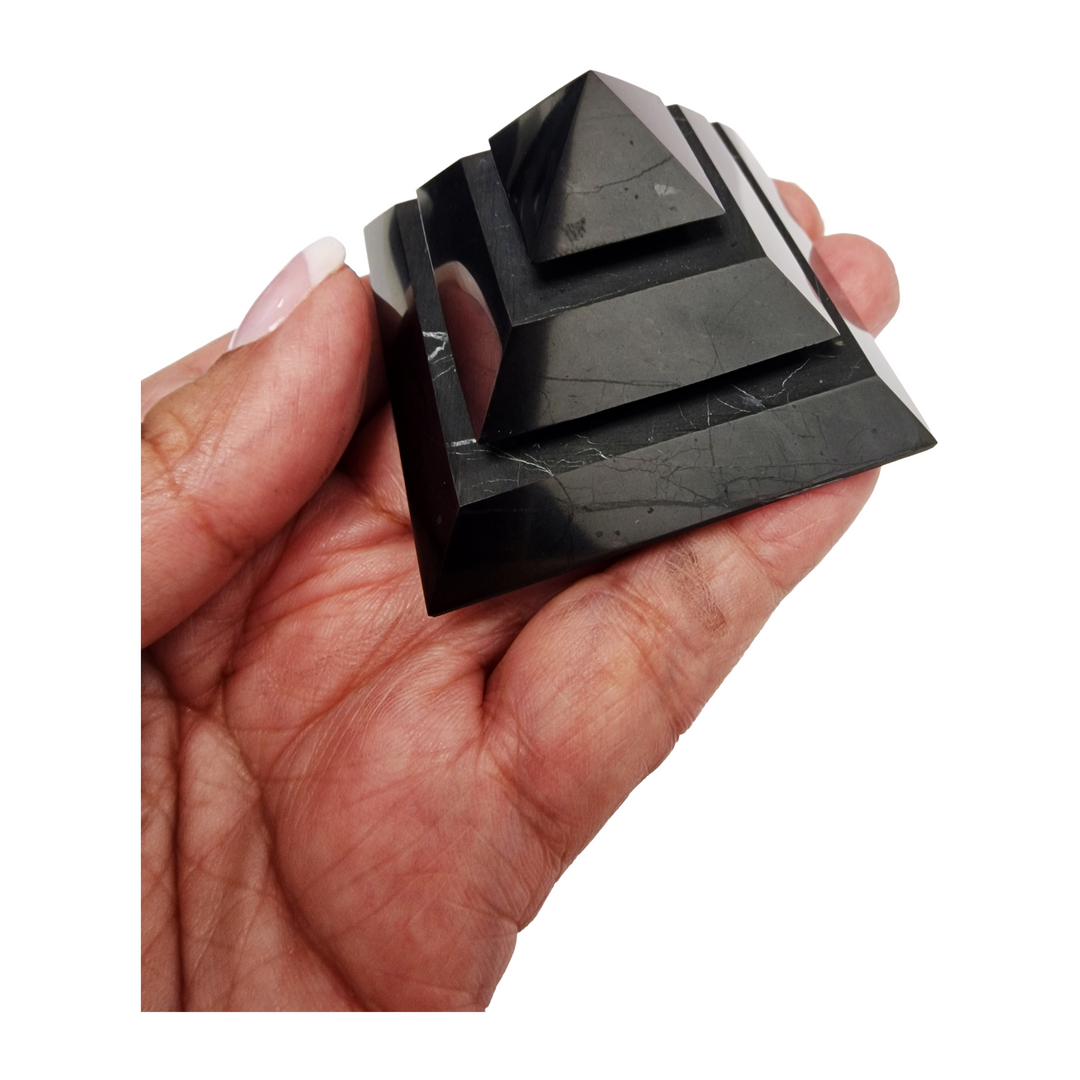Saqqara Shungite Pyramid 50mm on hand for size reference, grounding and EMF protection crystal