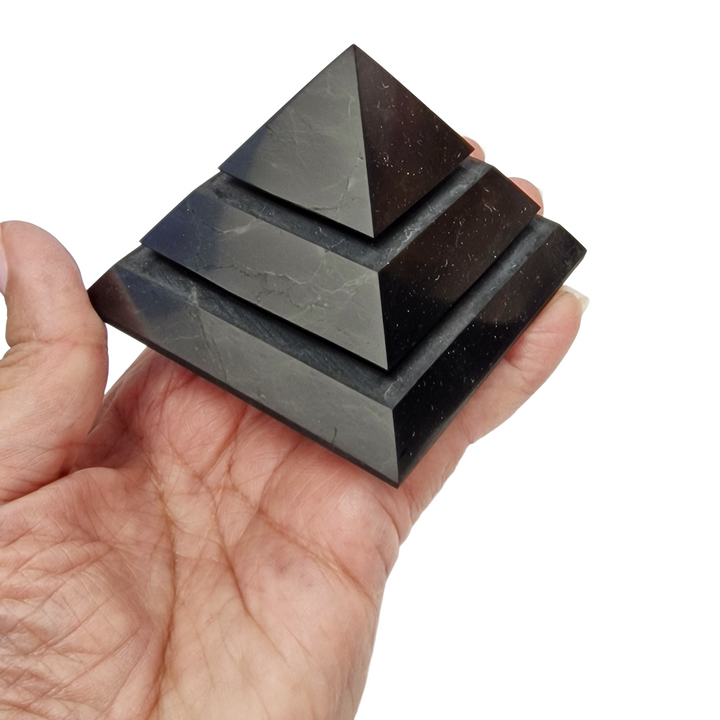 Shungite 70mm Saqqara Pyramid on hand for size reference, grounding and EMF protection crystal