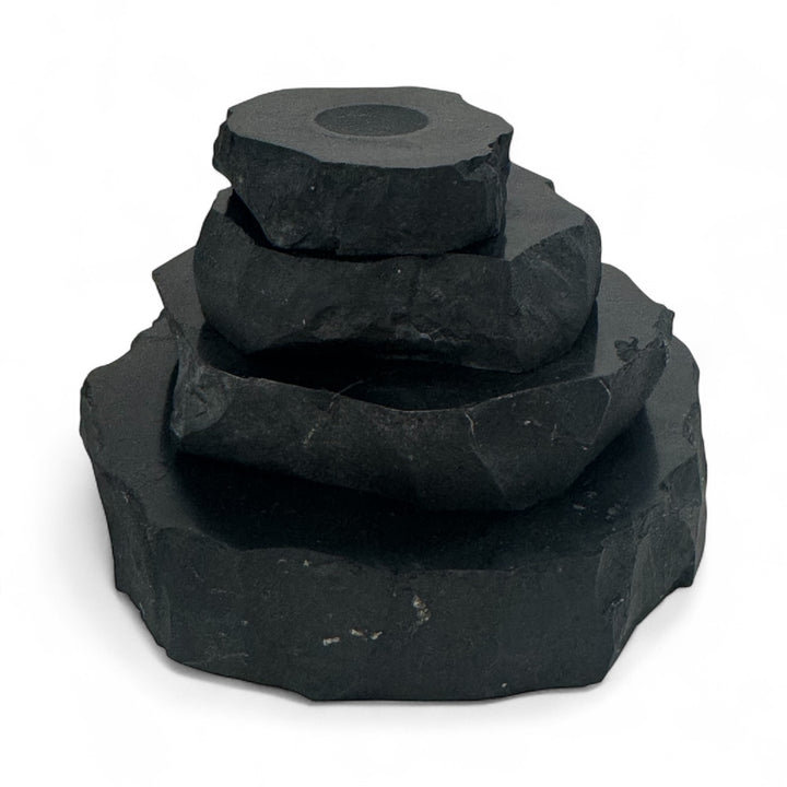 Stack of natural shungite bases in different sizes (small, medium, large, x-large) with carved circular indent for crystal spheres.