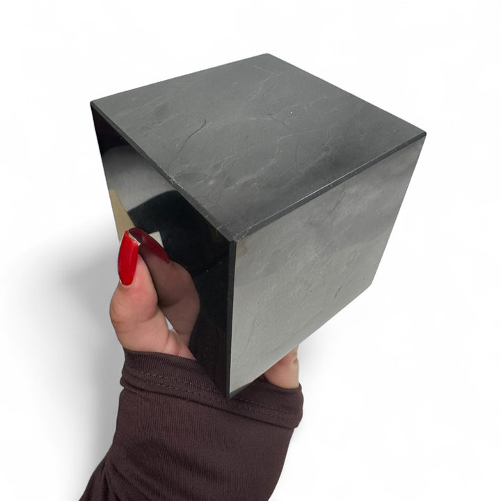 Hand holding an 80mm Shungite cube – shows scale of natural healing stone used for EMF protection and home decor.