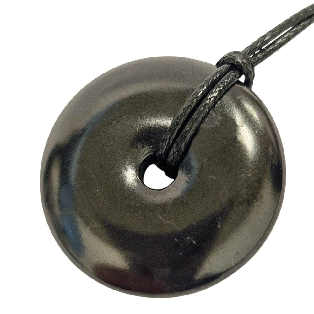 30mm Shungite donut pendant with black cord on hand, vegan-safe necklace for EMF protection