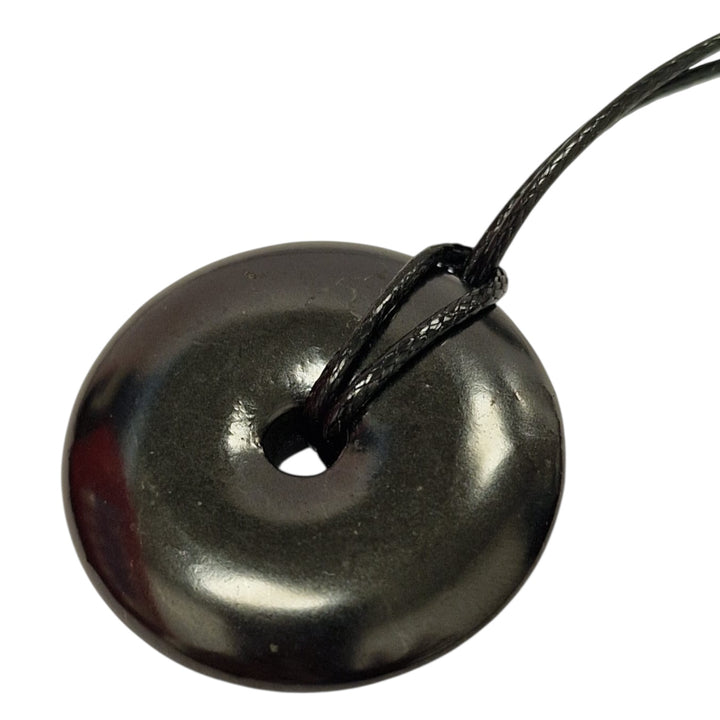 Shungite donut pendant on white background, polished 30mm crystal for grounding and balance