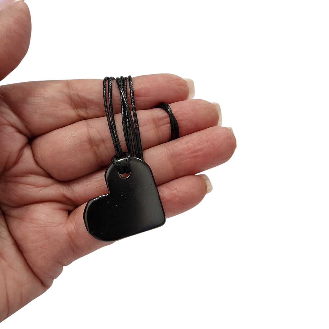 30mm heart-shaped Shungite pendant with black cotton cord on hand, vegan-safe EMF protection necklace