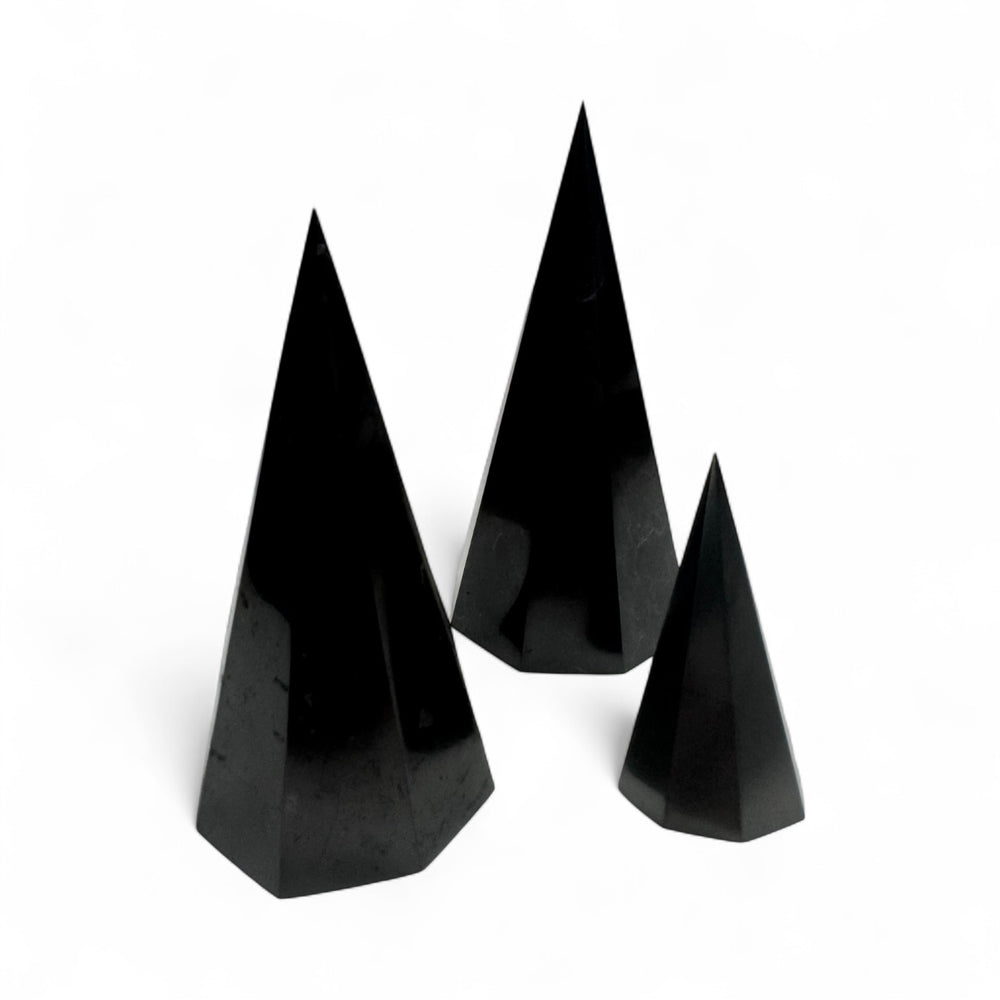 Three polished Shungite octagonal pyramids in different sizes (50mm, 10cm, and 12cm), natural black crystal energy tools for EMF protection, grounding, and meditation.
