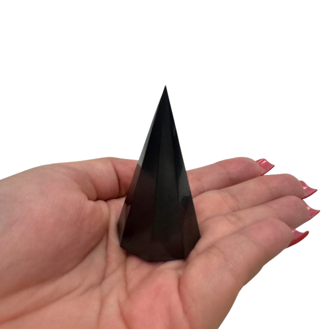 Small 50mm Shungite octagonal pyramid held in hand, natural EMF protection stone and meditation tool with sleek polished finish.