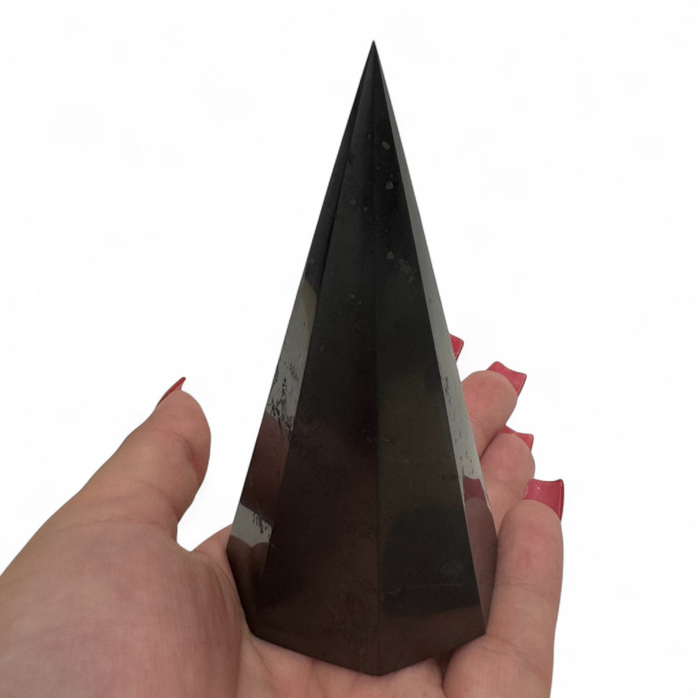 10cm polished octagonal shungite pyramid resting in hand, highlighting size and sleek finish of the protective crystal.
