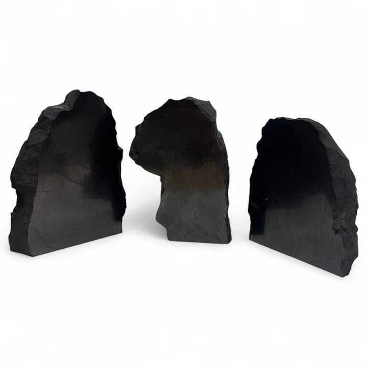 Set of three large one-face polished shungite crystals with smooth polished surfaces and raw sides, displayed on white background.