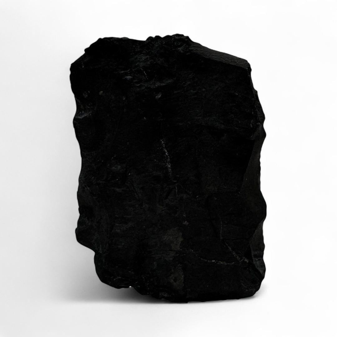 Back view of a raw shungite stone with unpolished natural black surface, highlighting its carbon-rich texture.