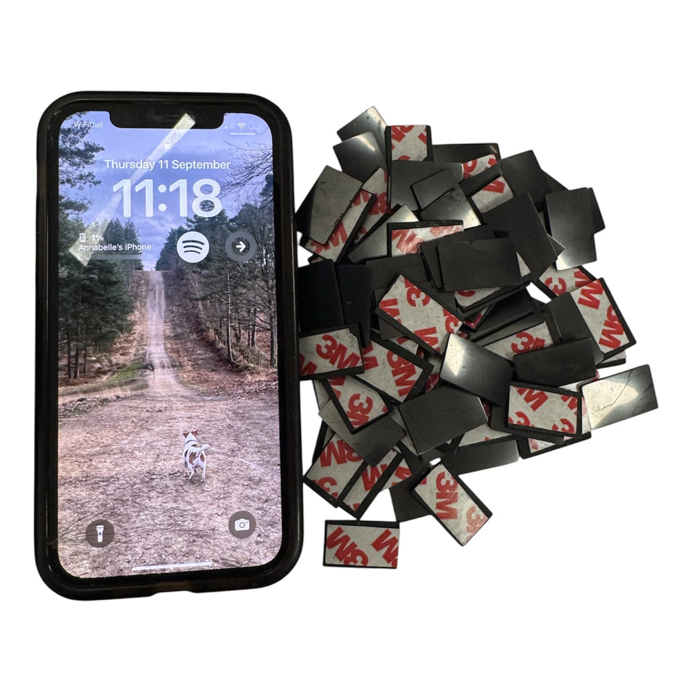 Shungite phone protection discs with adhesive backing next to a smartphone, used for EMF protection, radiation shielding, and energy balancing.