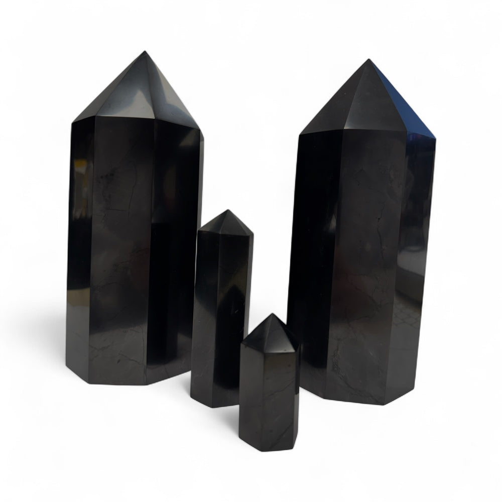 Collection of polished shungite towers in 5cm, 10cm, and 20cm sizes, showcasing size differences for grounding and EMF protection.