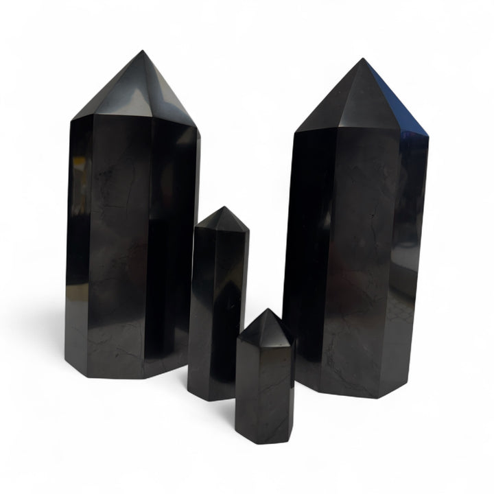 Collection of polished shungite towers in 5cm, 10cm, and 20cm sizes, showcasing size differences for grounding and EMF protection.