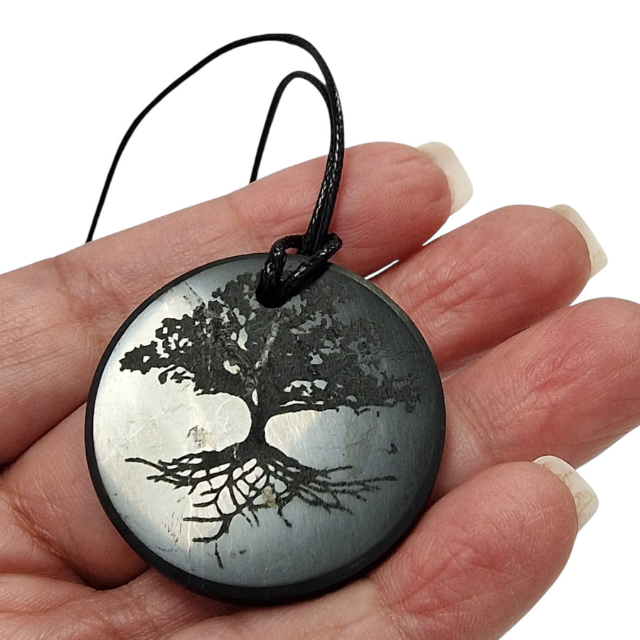 Tree of Life Shungite pendant with black cotton cord on hand, vegan-safe grounding jewellery for EMF protection