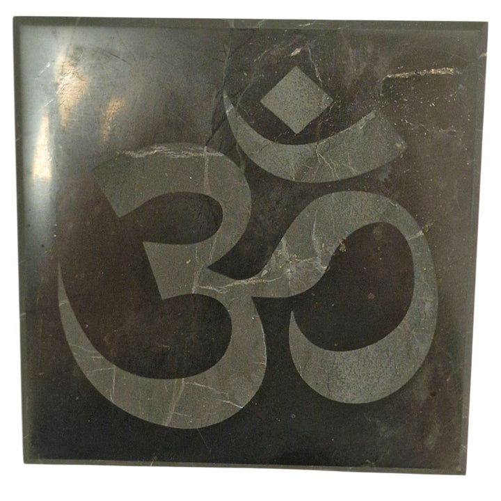 Shungite 10cm square disc with engraved Ohm symbol on white background, charging plate for crystals and jewellery