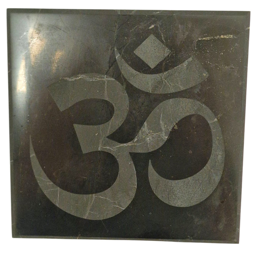 Shungite 10cm square disc with engraved Ohm symbol on white background, charging plate for crystals and jewellery