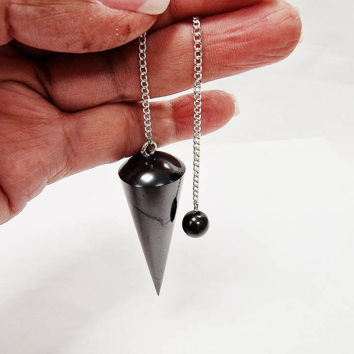 Close-up image of professional Shungite holding bead with silver chain, sharp precision pendulum tip visible