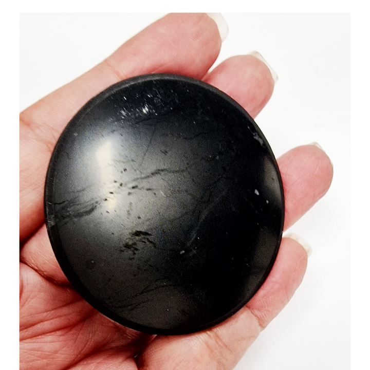 Shungite round 50mm protective slice on hand for size reference, EMF protection crystal